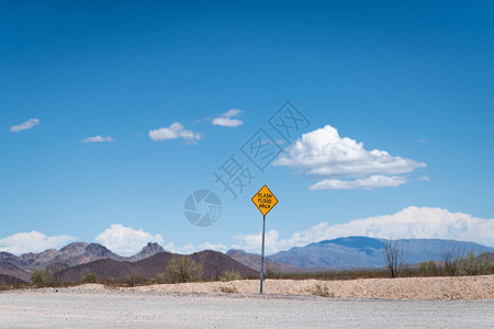 沙漠中一条空荡的道路上的山洪区警告标志图片