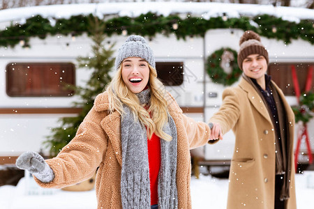 快乐的女人带领她快乐的男朋友在Capside的冬日户外观看降雪图片