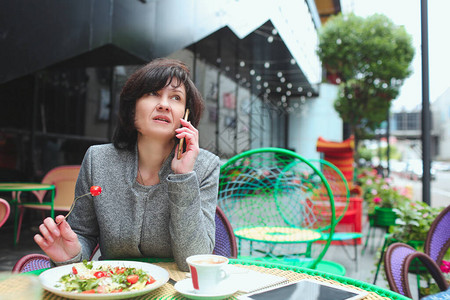 成熟的女人独自坐在咖啡馆或餐厅女商人通电话进行商务交谈午餐图片