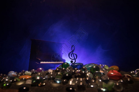 音乐概念音乐符号高音谱号不锈钢微型与雾背景上的彩色调光低光下的乐器图片