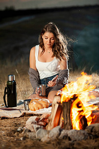 在火边喝茶的漂亮女孩温室休息热水茶自然中的浪图片