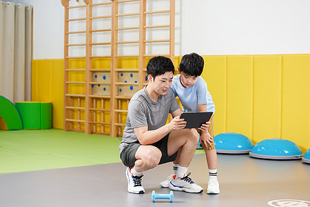 教练用平板电脑给男孩展示锻炼计划图片