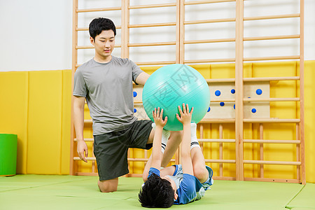 教练指导男孩使用瑜伽球训练图片素材