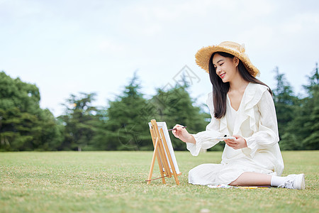 青年女性坐在草坪上绘画图片