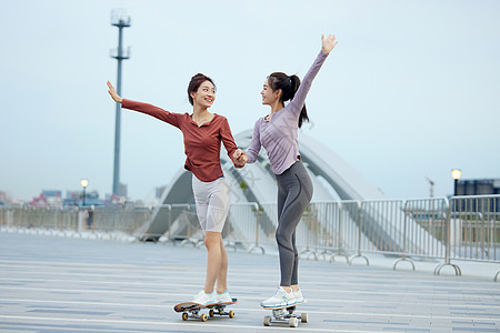 公园玩滑板美女户外玩滑板的年轻女性朋友背景