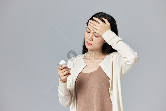 生病发烧的女性看耳温枪图片