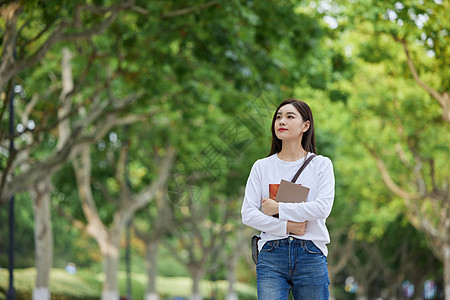 青年女休闲学习女青年校园里抱着书本背景