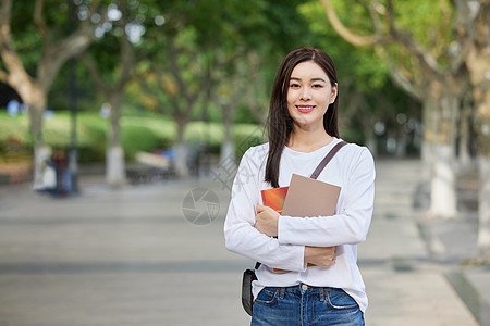 青年女休闲学习女青年校园里手拿书本背景