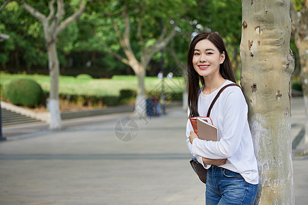 青年女休闲学习女青年校园里抱着书本背景