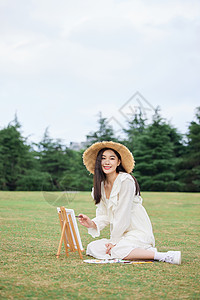 坐在草坪上绘画的青年女性图片