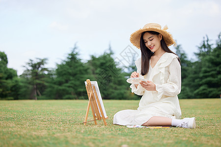 青年女性坐在草坪上绘画写生图片