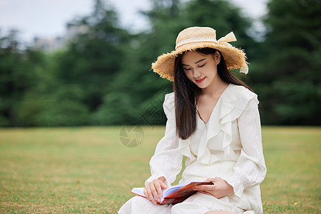 年轻美女户外草坪阅读高清图片
