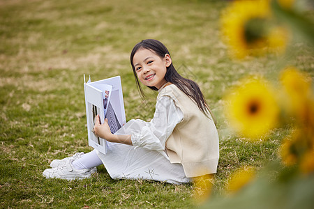 在草地上看书的小女孩图片