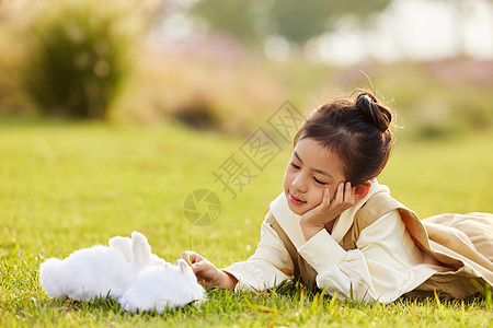 可爱女孩在草地上与兔子玩耍高清图片