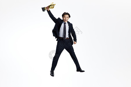 手举奖杯跳跃的商务男士图片