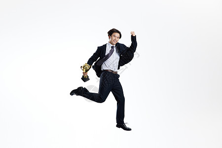 手举奖杯跳跃的商务青年男士背景图片