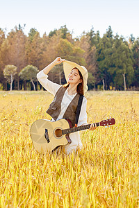 芒种站在稻田里手拿吉他的女性背景