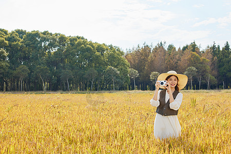 美女站在稻田里手拿照相机拍照图片