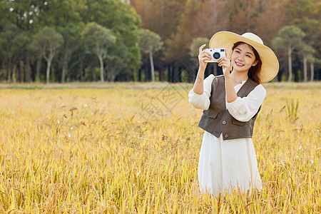 美女站在稻田里用照相机拍照图片