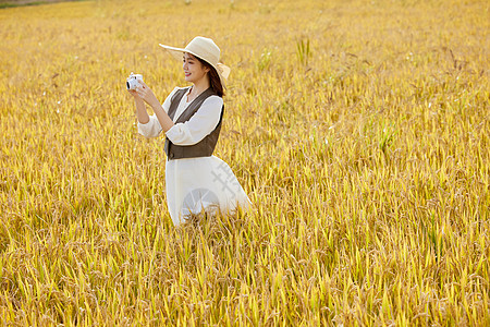 田野美女手拿照相机拍照图片