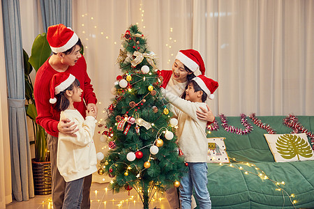 一家四口开心装饰圣诞树背景图片