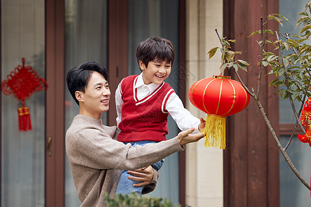 新年挂灯笼父亲和儿子在院子树上挂灯笼背景