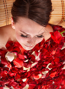 穿着玫瑰花瓣浴缸的美丽的年轻女图片