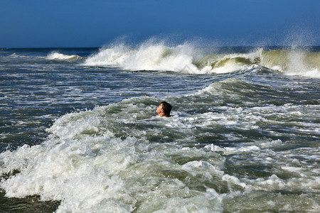 小男孩在海浪中冲浪图片
