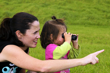 母亲和她的孩子用双筒望远镜看背景图片