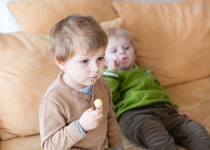 两个小兄弟男孩在电视上看电视在室内吃糖果有选择地关注图片