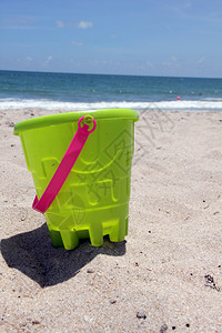 阳光沙滩上的绿色玩具桶图片
