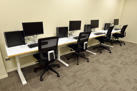 带有空工作站办公桌和椅子的计算机实验室图片