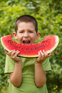 快乐的孩子吃着大红片西瓜图片