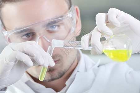 有吸引力的年轻博士生科学家在化学实验室观察溶液蒸馏后的黄色指图片