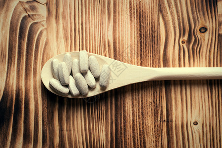 维生素或补剂在木勺老式木制板上图片