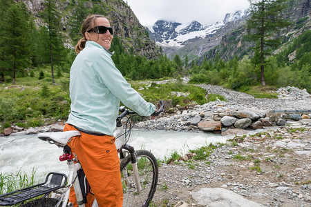 妇女骑自行车者享受山图片