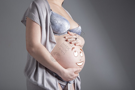 孕妇在她的肚子上显示图像滑稽的脸图片
