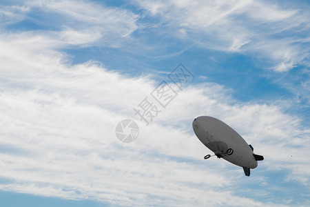 飞艇在蓝色多云的天空中飞行背景图片