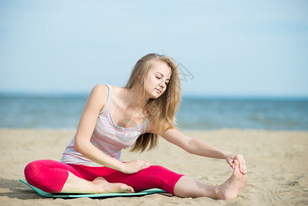 练习瑜伽的年轻女士美丽的女人在夏天的沙滩上摆姿势在海洋岸附近锻炼美丽适合棕褐色的女孩户外健身模型高加索种背景图片