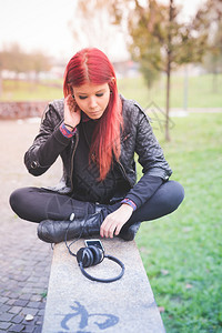 年轻漂亮的红发委内瑞拉女人坐在公园里戴图片