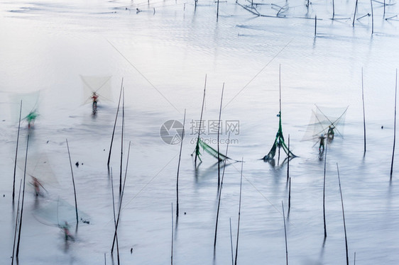 渔民早上在Xiapu海岸的浅水用手网捕捉鱼图片