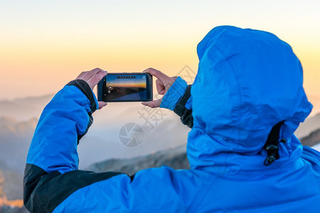 女人用手机拍山上的照片在山图片