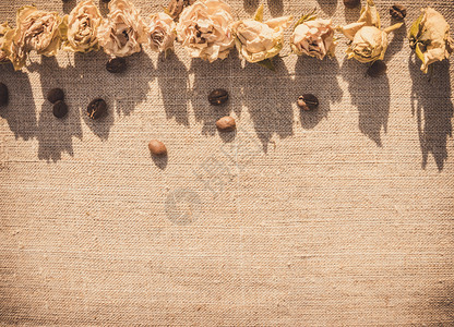 白玫瑰的干花蕾和天然亚麻织物背景上散落的咖啡豆小型私密浪漫餐厅的室内设背景图片