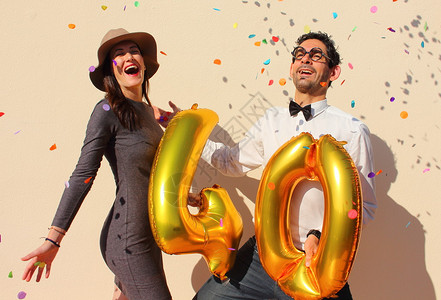 开朗的夫妇庆祝四十岁生日与的大气球和多彩小纸片在空气中背景图片