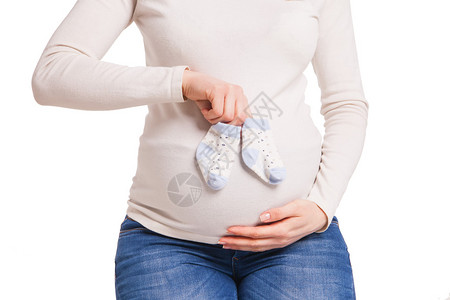 快乐的孕妇的手拿着小袜子在白色上图片
