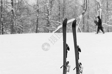 下雪了背景是被雪覆盖的森林滑雪者手里拿着他的滑雪板经过专注于顶部的天图片