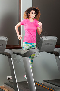 美丽的女人在健身房的运动机上跑步作为心图片