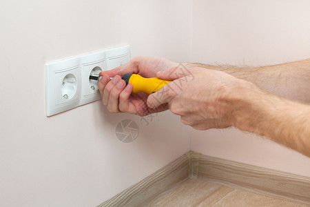 安装墙壁电源插座的电工的手图片