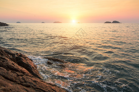 在海中的热带岩石海岸上的日落图片