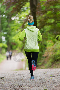 运动型年轻女赛跑者在森林里奔跑的女人在大自然中户外锻炼期间的女跑步者户外健身模型健背景图片